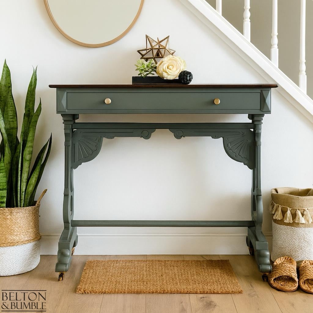 Hallway with a restored green console table, dark wood top, basket, rug, and soft décor creating a sustainable interior.