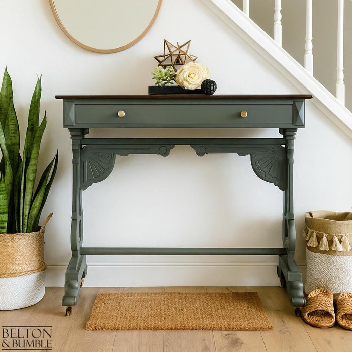 Hallway with a restored green console table, dark wood top, basket, rug, and soft décor creating a sustainable interior.