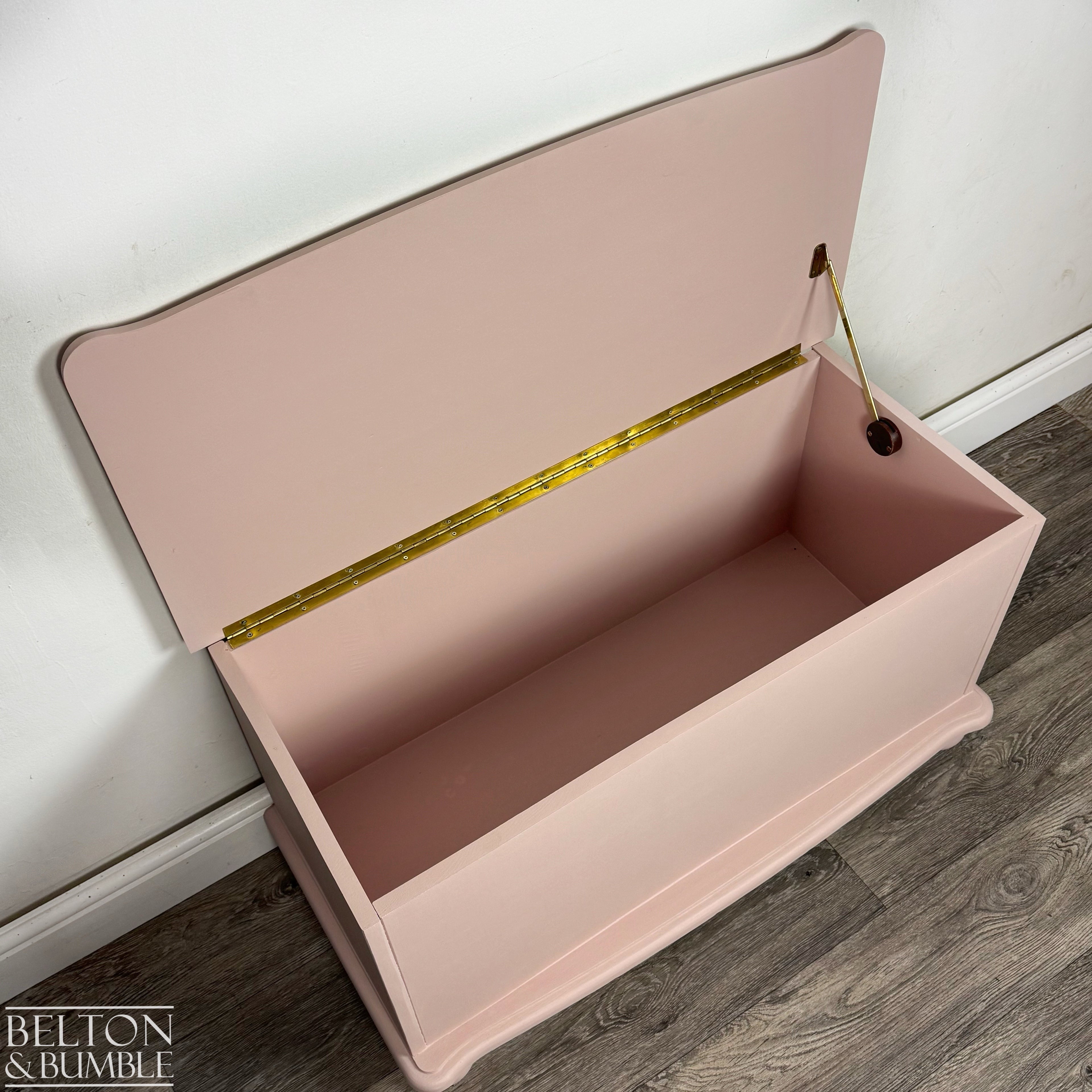 Overhead angle showing inside of pink painted storage box with gold-tone hinge hardware.