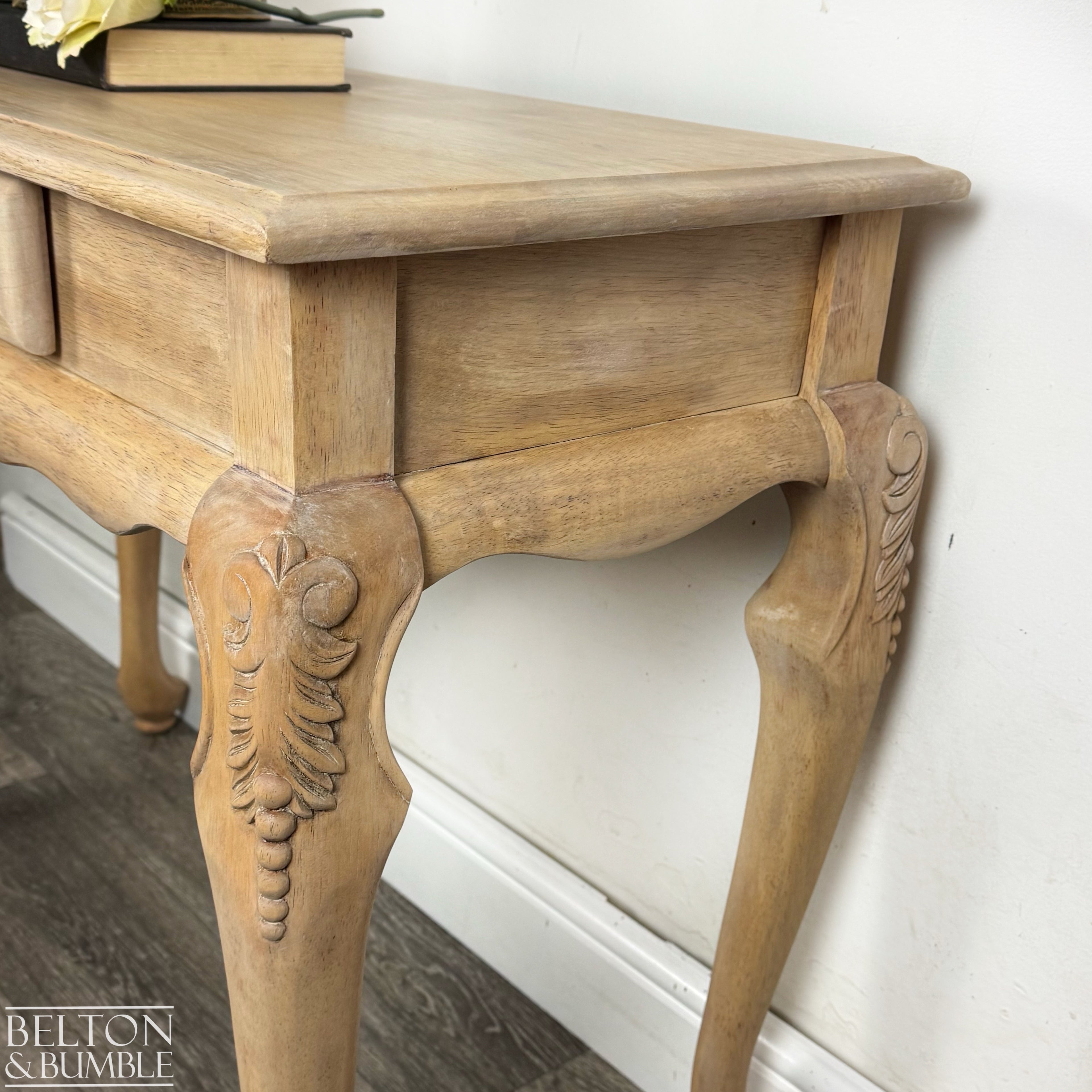 Close-up of carved cabriole leg on the console table, highlighting the soft natural wood tones and craftsmanship.