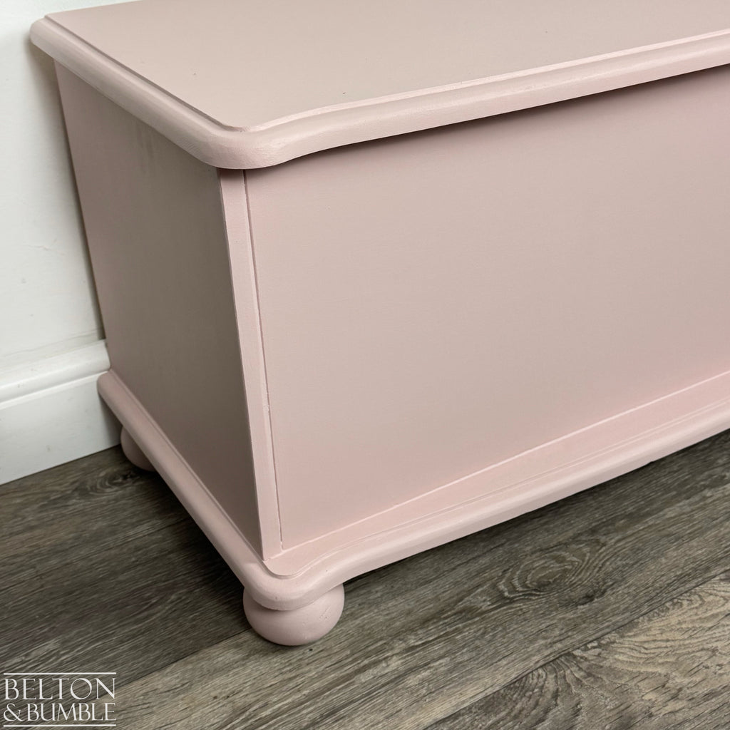 Close-up of the corner of the pink storage chest showing smooth painted finish and rounded edge detail.