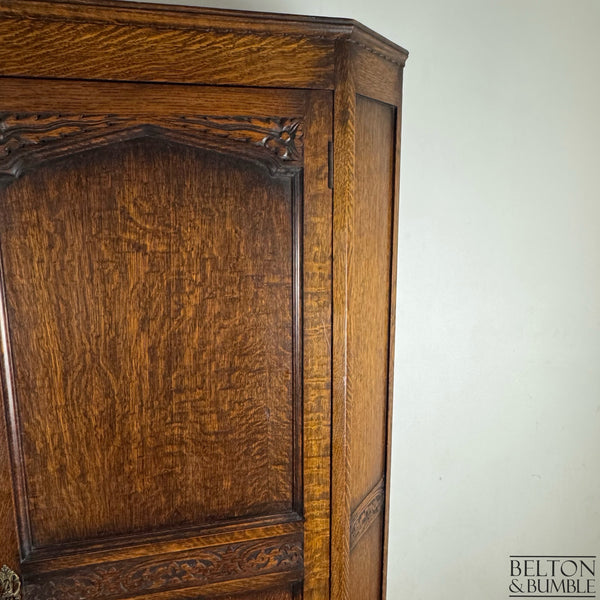 Close-up of the carved upper panel and rich oak texture on the wardrobe door.