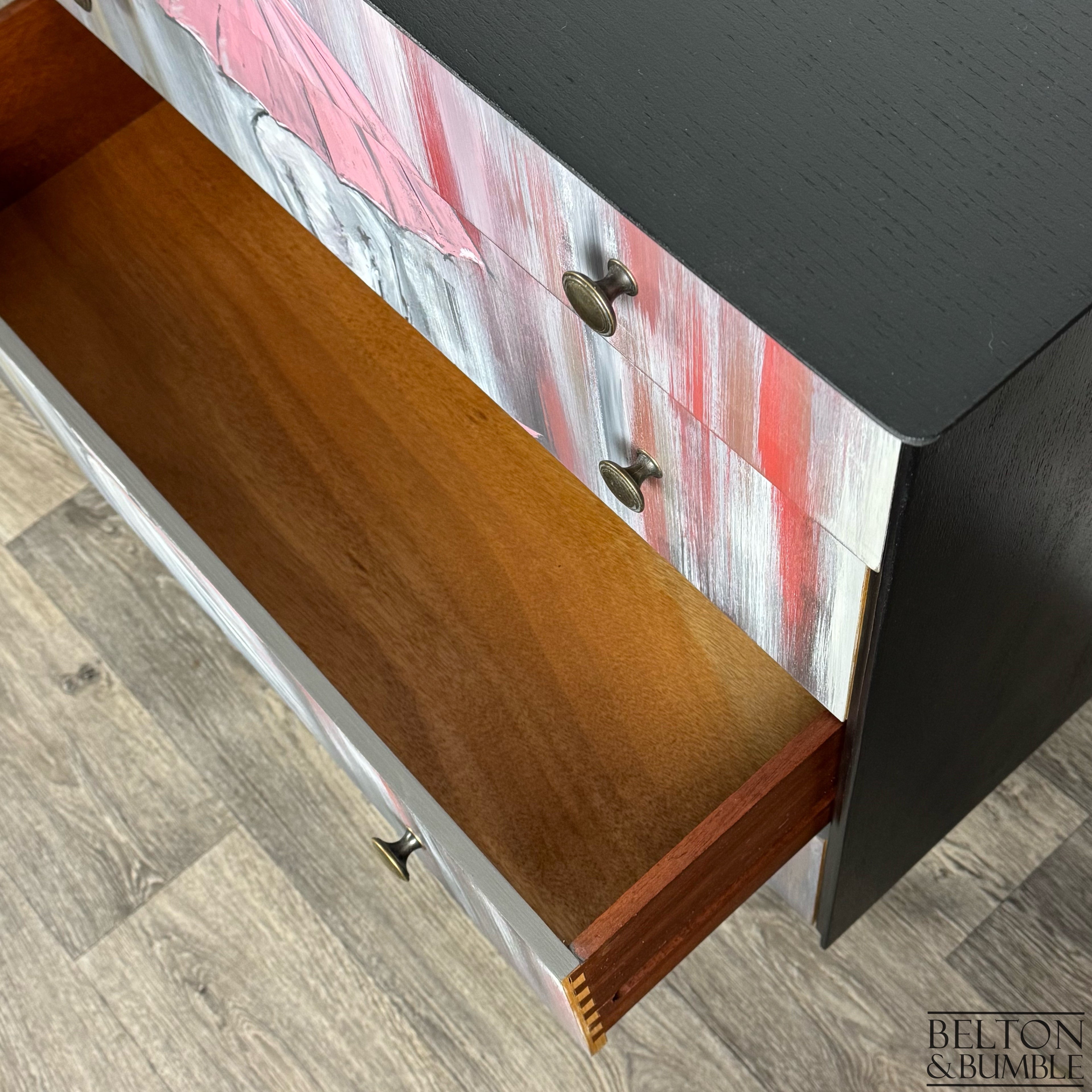 Chest with open drawer showing wood grain interior and umbrella design across the fronts.