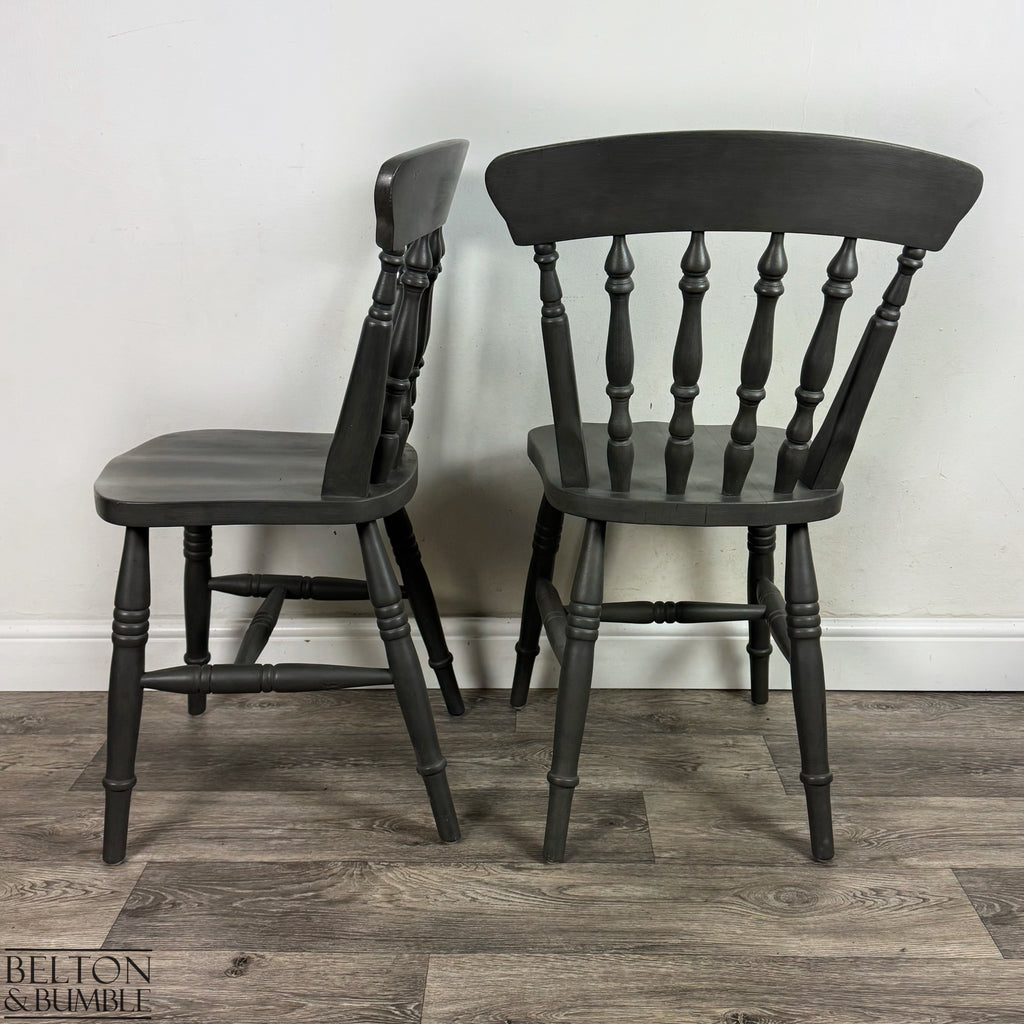 Side and back angle of two dark grey spindle-back farmhouse chairs.