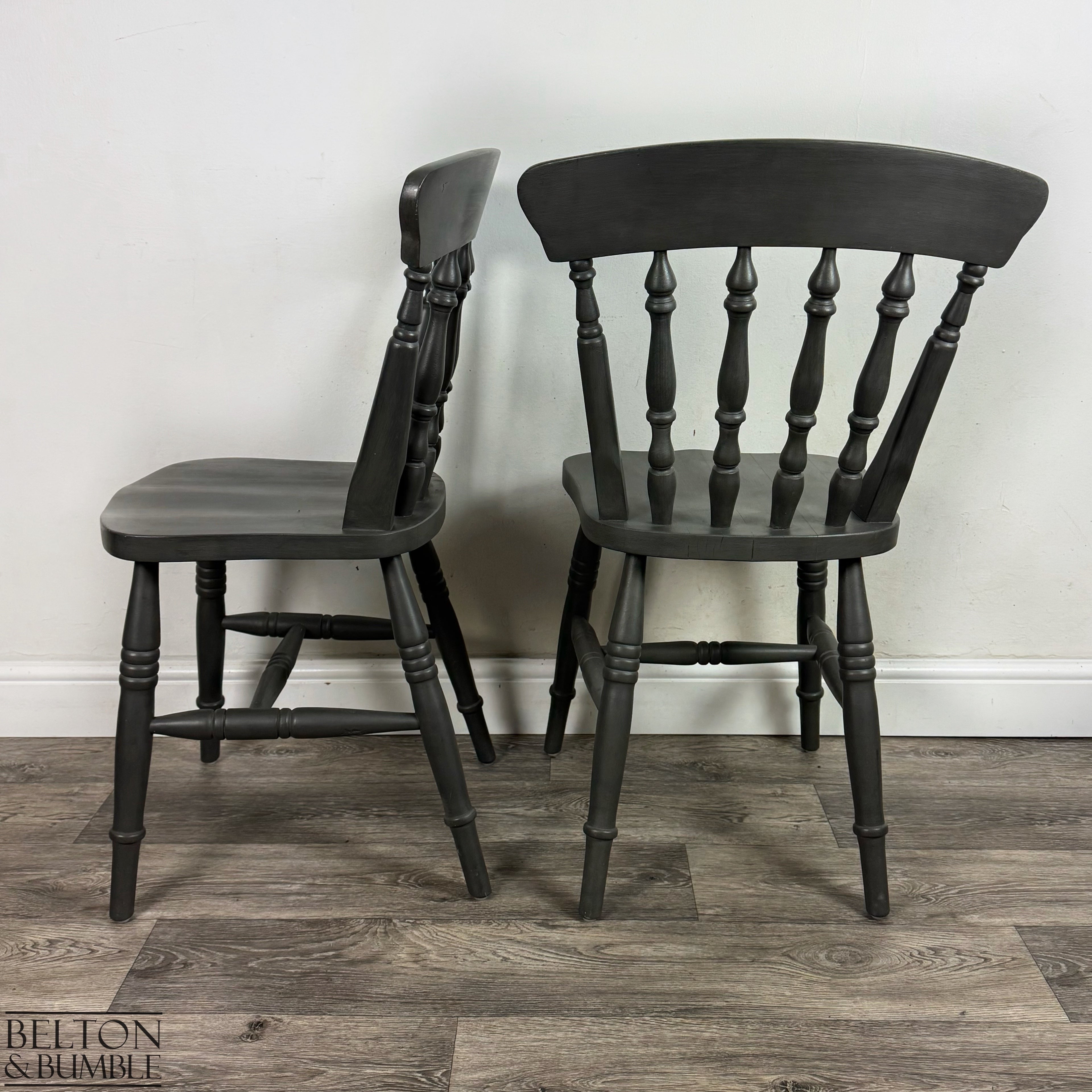 Side and back angle of two dark grey spindle-back farmhouse chairs.