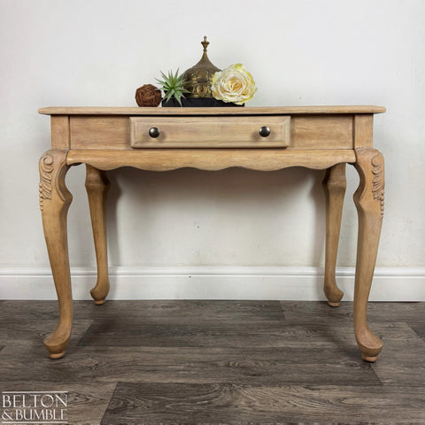 Natural light wood console table with carved legs and single drawer, styled with neutral decorative accents.