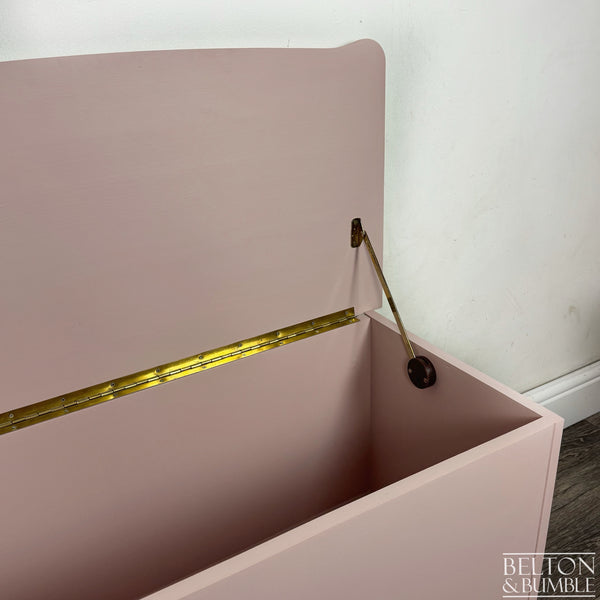 Inside view of blush pink blanket box showing open lid with polished brass hinges and stay arm.