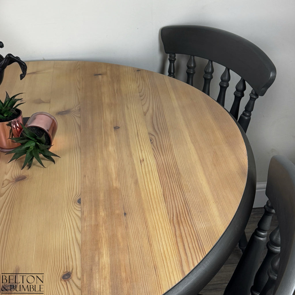 Detailed view of the natural pine tabletop and dark grey painted farmhouse chairs.