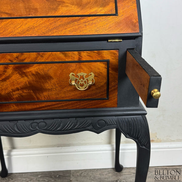 Restored bureau showing burr walnut drawer, gold handles, and carved black legs