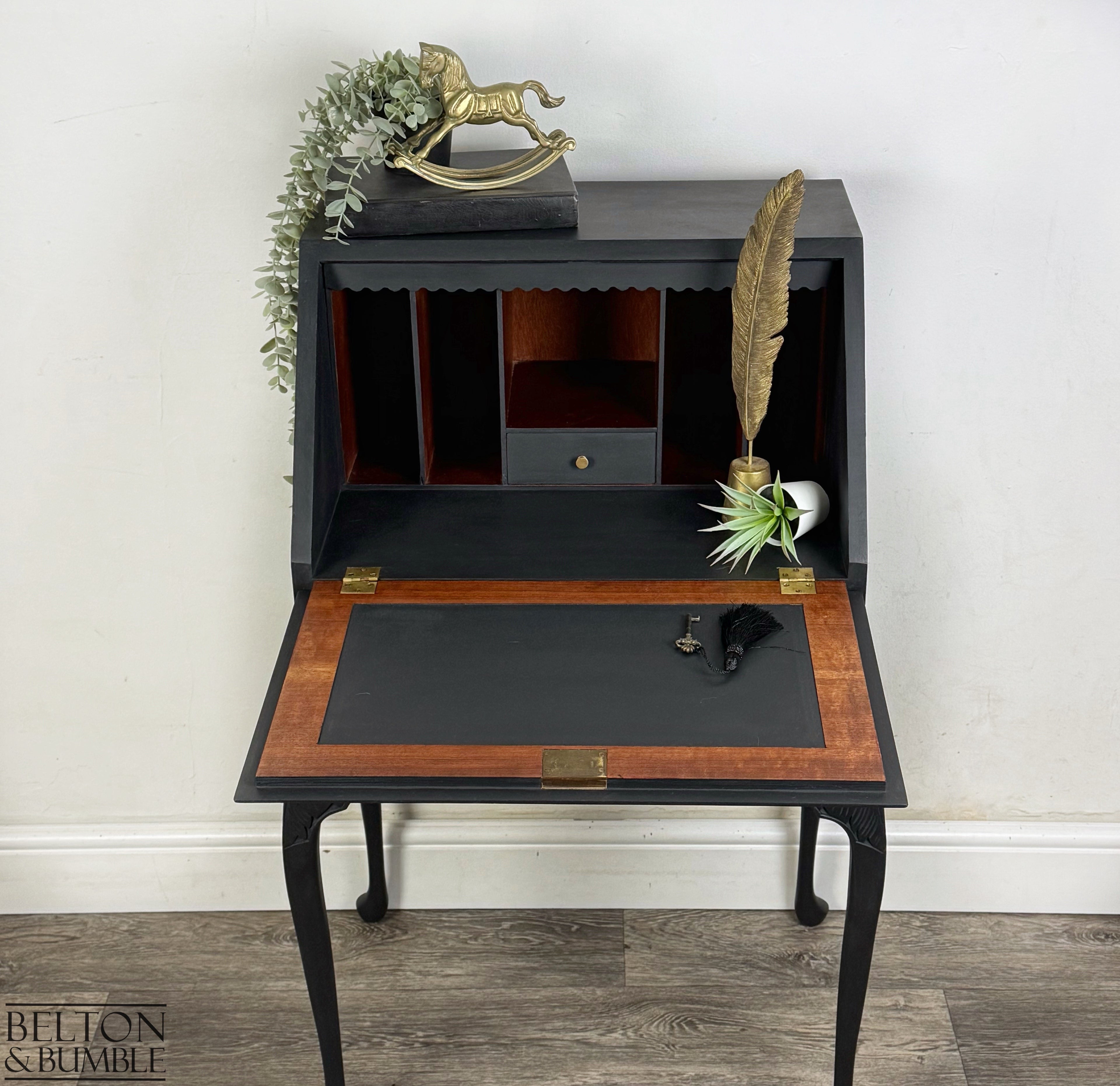 Close-up of restored bureau interior showing pigeonholes, small drawer, and black writing surface with walnut trim