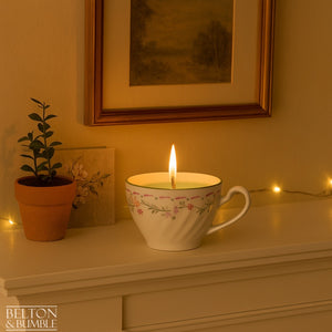 Soy Wax Vintage Teacup Candles with Green Apple Scent - Lit soy wax candle with green apple scent in a delicate floral vintage teacup, glowing softly on a mantel with potted plants.