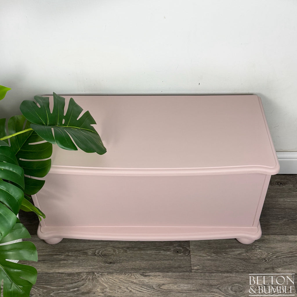 Overhead view of blush pink blanket chest showing smooth painted finish and softly curved edges.