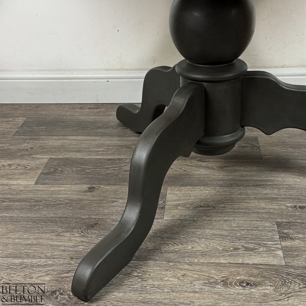 Underside view showing the turned pedestal column and natural pine tabletop edge.